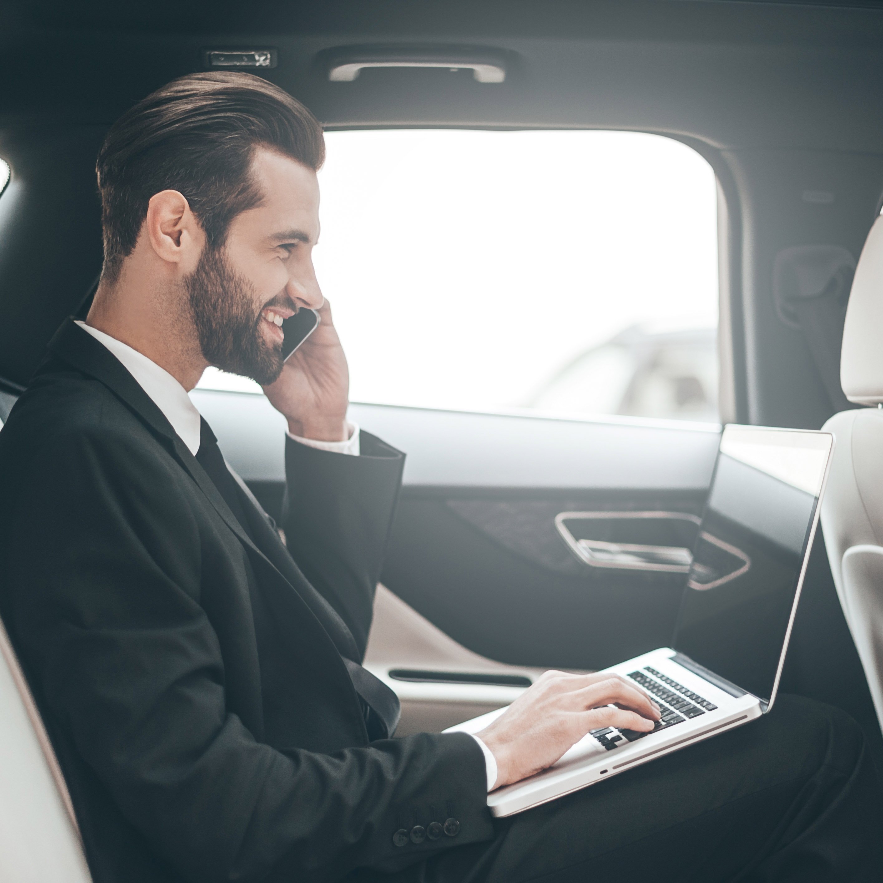time-make-decision-confident-young-businessman-working-his-laptop-talking-phone-while-sitting-car